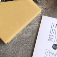 Birthday card reading happy birthday to my favourite person next to a wrapped gift and pink roses