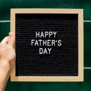 Happy Father's Day letter board in wooden frame held against green wall