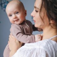 Mother joyfully holding her baby in a cozy indoor setting