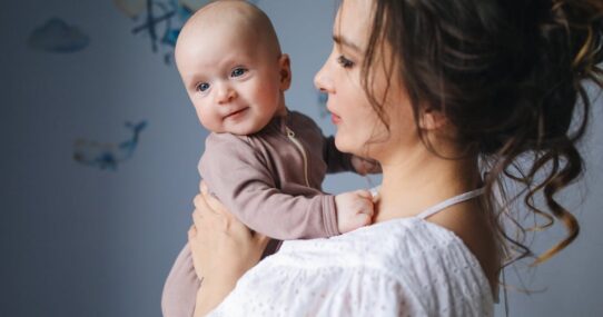 Mother joyfully holding her baby in a cozy indoor setting