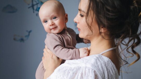 Mother joyfully holding her baby in a cozy indoor setting